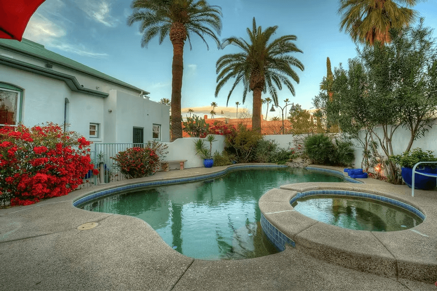 A serene outdoor pool surrounded by palm trees and vibrant flowers.
